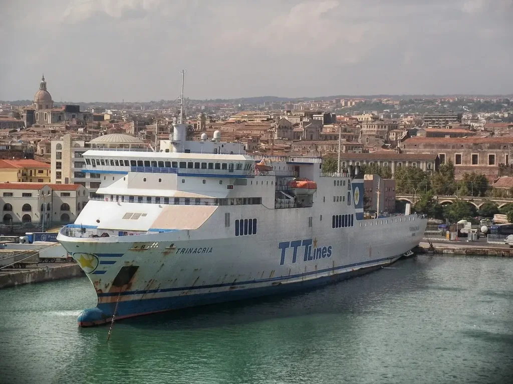 a large white ship in a body of water with a city in the background